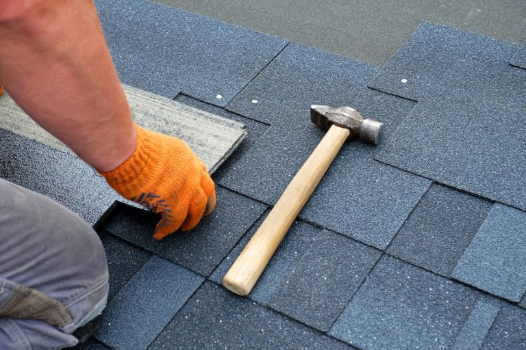 Contractor hands installing bitumen roof shingles using hammer, Edina, MN