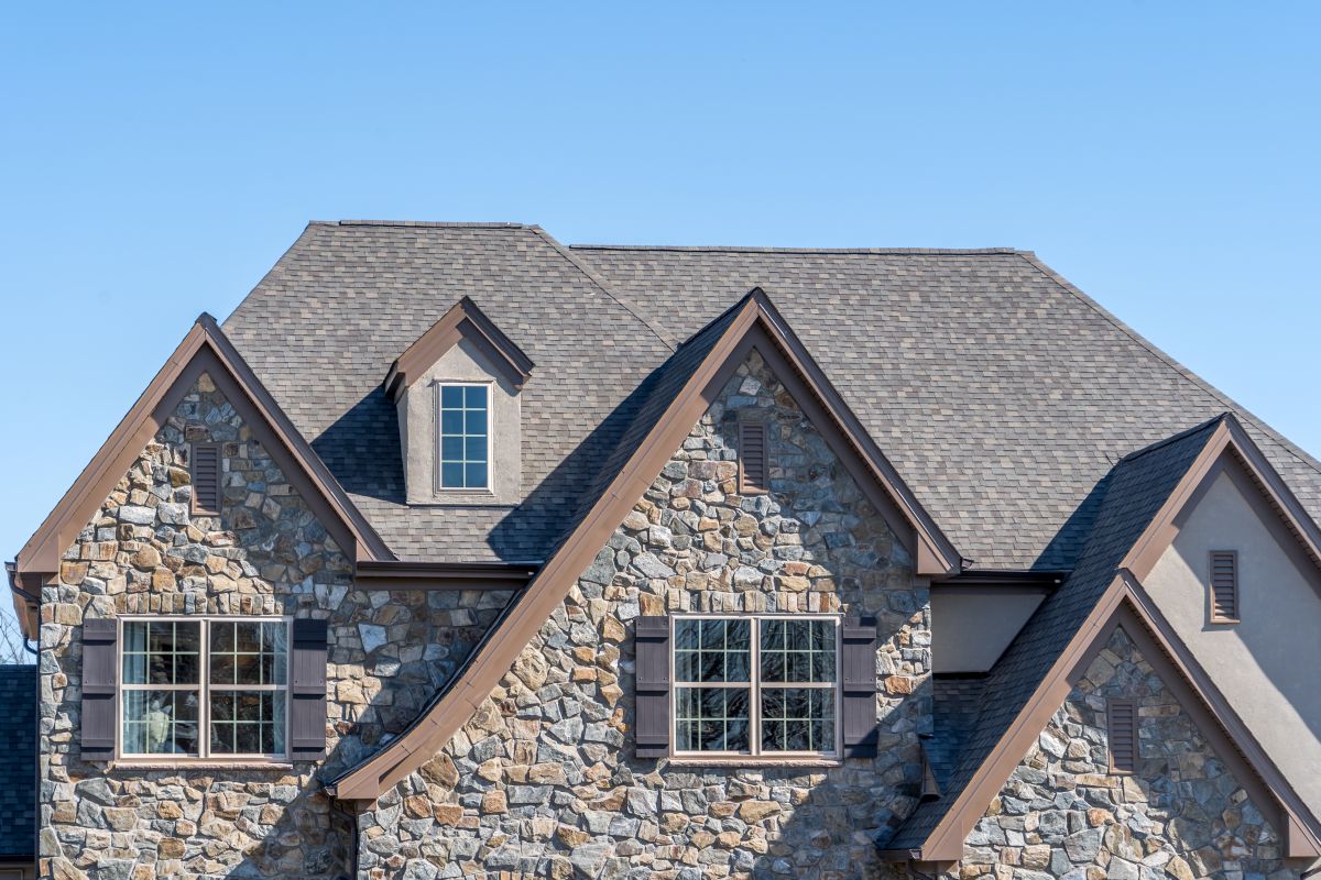 Double gable with dark stone veneer siding, with triangle shape peaks, on a pitched roof attic at an American single family home, Edina