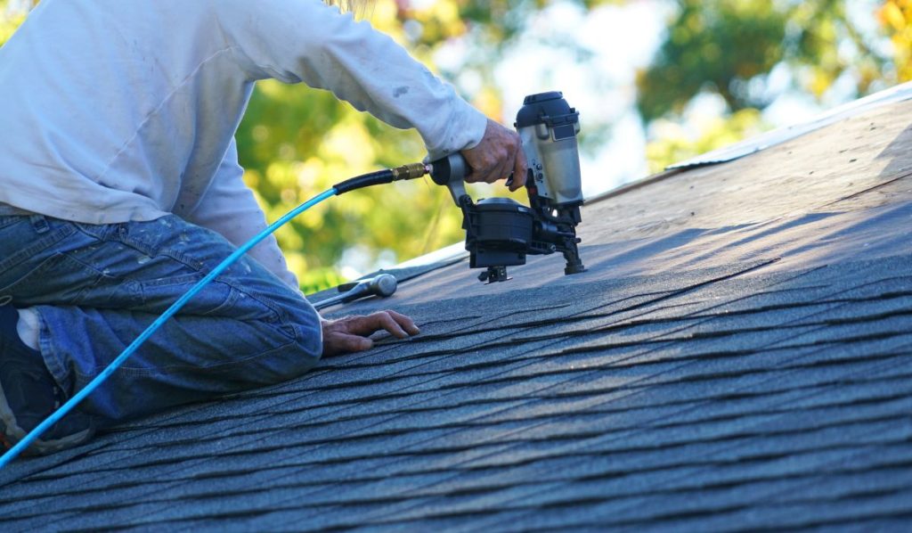 roofer repairing asphalt roof with nail gun. Edina, MN